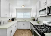 Thumbnail 1 of 52 - a kitchen with white cabinets and a stove and a microwave