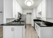 Thumbnail 1 of 19 - a white kitchen with white cabinets and black counter tops