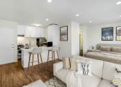 Thumbnail 8 of 102 - a living room with a couch and a kitchen and a bed