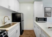 Thumbnail 7 of 102 - a kitchen with white cabinets and a sink and a refrigerator