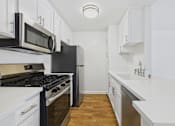 Thumbnail 46 of 60 - A kitchen with black and white appliances and wooden floors.