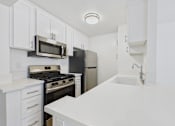 Thumbnail 45 of 60 - A kitchen with white cabinets and appliances.