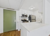 Thumbnail 47 of 60 - A kitchen with a green door and white countertops.