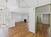 Thumbnail 27 of 60 - A room with a white kitchen and wooden floors.