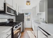 Thumbnail 25 of 60 - A modern kitchen with white cabinets and black appliances.
