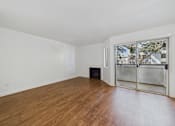 Thumbnail 28 of 60 - A room with wooden flooring and a window with a view of trees and buildings outside.