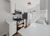 Thumbnail 24 of 60 - A white kitchen with a black stove and a black refrigerator.