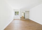 Thumbnail 42 of 60 - A room with white walls and wooden flooring with a doorway leading to another room.