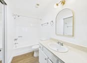 Thumbnail 44 of 60 - A white bathroom with a sink, mirror, and toilet.