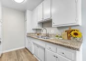Thumbnail 2 of 18 - A kitchen with white cabinets and a granite countertop.