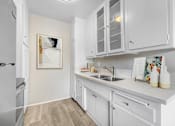 Thumbnail 9 of 18 - A kitchen with white cabinets and a fridge.