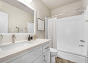 Thumbnail 12 of 18 - A white bathroom with a sink, toilet, and bathtub.
