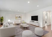Thumbnail 5 of 67 - A modern living room with a white sofa, a coffee table, and a TV.