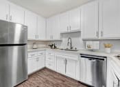 Thumbnail 1 of 67 - A kitchen with white cabinets and a stainless steel refrigerator.