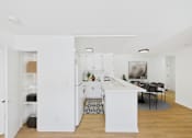 Thumbnail 6 of 38 - A kitchen with white cabinets and a dining table with chairs.