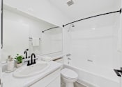 Thumbnail 45 of 46 - A white bathroom with a toilet, sink, and bathtub.