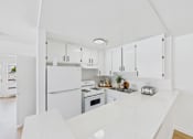 Thumbnail 38 of 46 - A white kitchen with a refrigerator, oven, and sink.