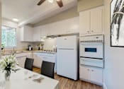 Thumbnail 11 of 23 - a white kitchen with white appliances and a white table