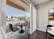 Thumbnail 17 of 36 - A balcony with a table and chairs overlooking a cityscape.
