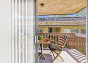 Thumbnail 7 of 50 - A wooden chair is on a patio with a table in front of a house.