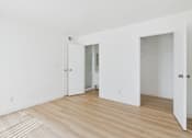Thumbnail 30 of 50 - A room with white walls and wooden flooring with two doors.