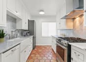 Thumbnail 1 of 17 - a kitchen with white cabinets and a stove and a window