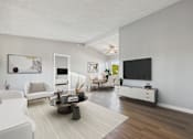 Thumbnail 5 of 23 - A living room with a white couch, a coffee table, and a flat screen TV.