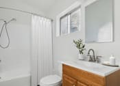 Thumbnail 9 of 23 - A white bathroom with a toilet, sink, and shower.
