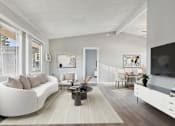 Thumbnail 3 of 23 - A modern living room with a white sofa and a coffee table.