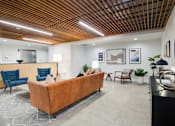 Thumbnail 5 of 119 - A modern waiting room with a wooden ceiling and a long brown couch.