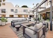 Thumbnail 1 of 119 - A modern outdoor seating area with a wooden floor and grey cushions.