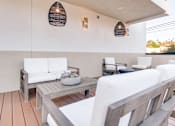 Thumbnail 10 of 119 - A white couch is on a wooden deck with a table and chairs.