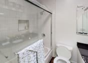 Thumbnail 21 of 34 - A white toilet sits next to a glass shower stall.