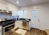Thumbnail 12 of 34 - A modern kitchen with white cabinets and stainless steel appliances.