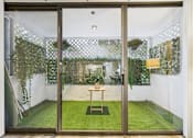 Thumbnail 68 of 127 - A glass door with a table and chairs in the garden.
