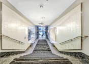 Thumbnail 86 of 95 - A long hallway with a carpeted staircase and a metal railing.