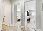Thumbnail 7 of 15 - A hallway with a white door and a mirror on the wall.