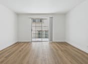 Thumbnail 14 of 29 - A room with wooden floors and a door leading to a balcony.