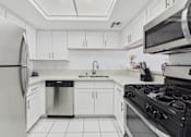 Thumbnail 7 of 29 - A modern kitchen with white cabinets and appliances.