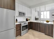 Thumbnail 2 of 31 - A modern kitchen with a stainless steel refrigerator and wooden cabinets.