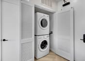 Thumbnail 8 of 31 - A white laundry room with a washer and dryer stacked on top of each other.
