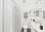 Thumbnail 10 of 34 - A white bathroom with a toilet, sink, and shower.