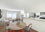 Thumbnail 3 of 6 - a living room with a table and a couch and a kitchen