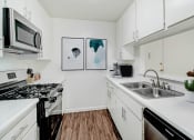 Thumbnail 2 of 6 - a kitchen with white cabinets and a sink and a microwave
