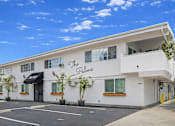 Thumbnail 1 of 14 - The Palms building has a black awning and a yellow door.