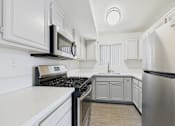 Thumbnail 26 of 115 - A modern kitchen with white cabinets and stainless steel appliances.