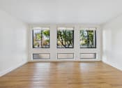 Thumbnail 61 of 92 - A room with wooden floors and three windows.