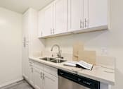 Thumbnail 10 of 33 - A kitchen with white cabinets and a black dishwasher.