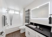 Thumbnail 19 of 19 - A white bathroom with a black counter top and a white toilet.