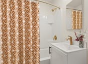 Thumbnail 54 of 66 - a bathroom with a white sink and gold shower curtain
